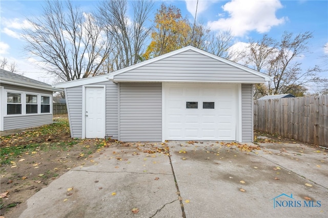 detached garage featuring driveway and fence