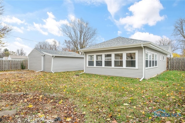 rear view of house featuring a yard, roof with shingles, and fence private yard