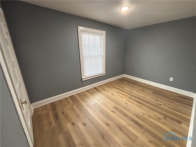 unfurnished room with baseboards and wood finished floors