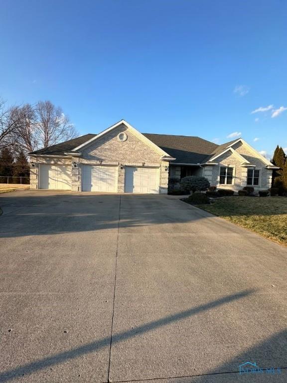 ranch-style house with driveway, brick siding, and an attached garage