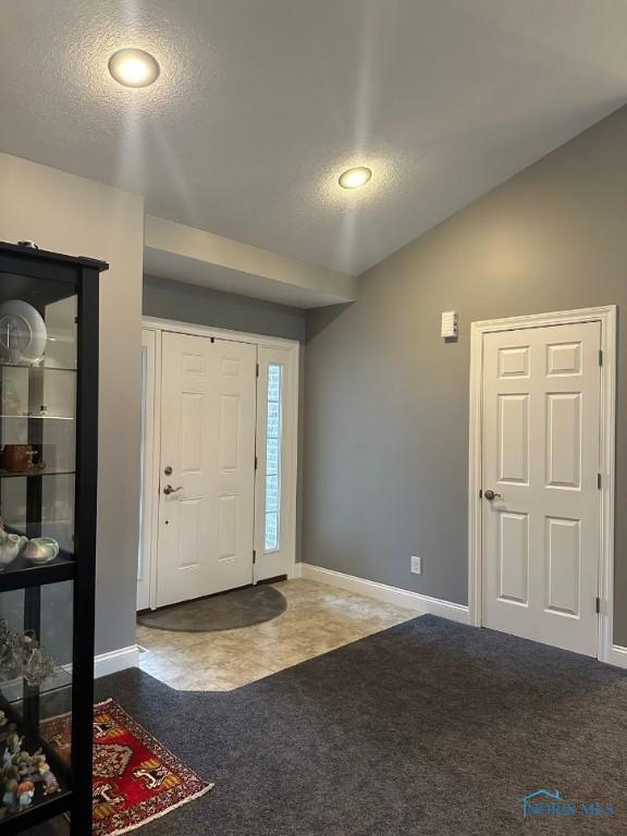 entryway with baseboards, carpet flooring, and vaulted ceiling