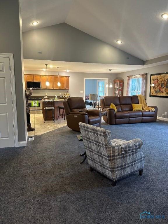 living area with light carpet, high vaulted ceiling, and baseboards