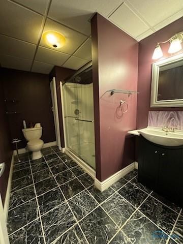 bathroom featuring a drop ceiling, vanity, toilet, and a shower stall