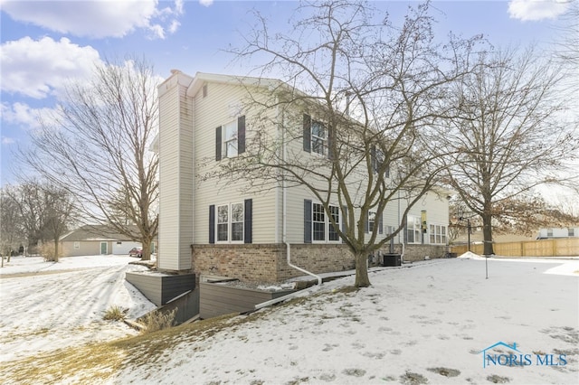 view of front of home featuring brick siding, a chimney, and central AC unit