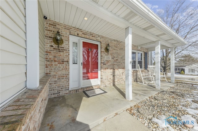 entrance to property with covered porch and brick siding