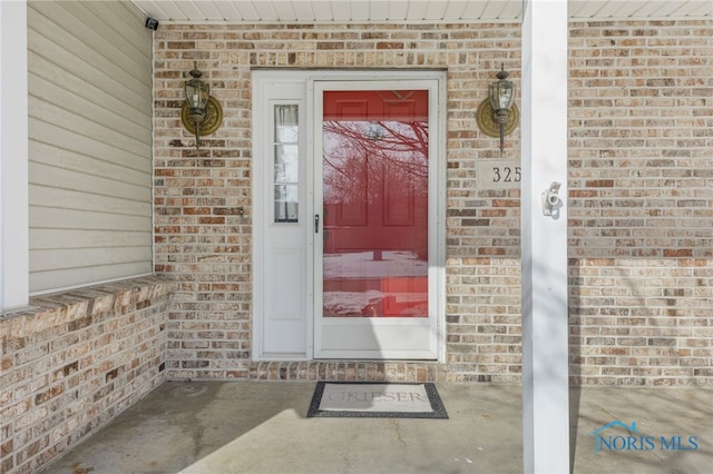 view of exterior entry featuring brick siding