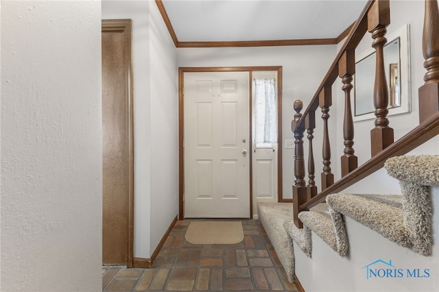 foyer entrance featuring brick floor, stairs, baseboards, and crown molding