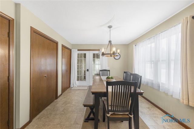 dining room featuring baseboards, a chandelier, and french doors