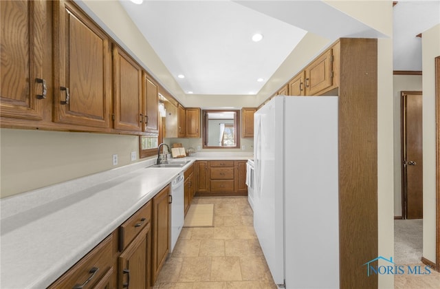 kitchen featuring recessed lighting, white appliances, a sink, light countertops, and brown cabinets