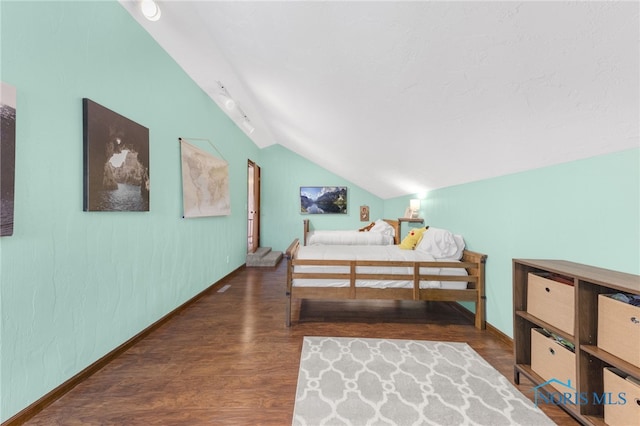 bedroom with vaulted ceiling, baseboards, and wood finished floors