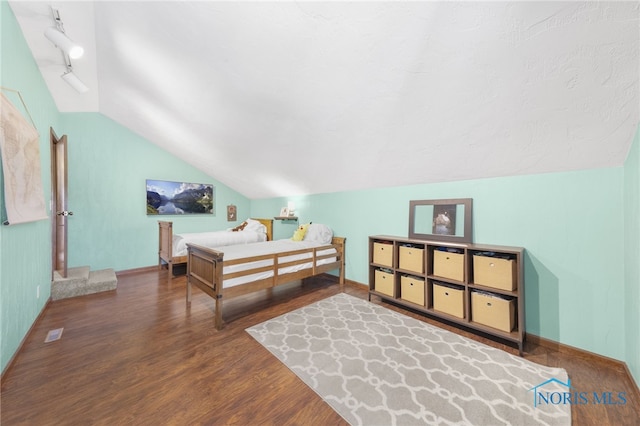 bedroom with rail lighting, baseboards, vaulted ceiling, and wood finished floors