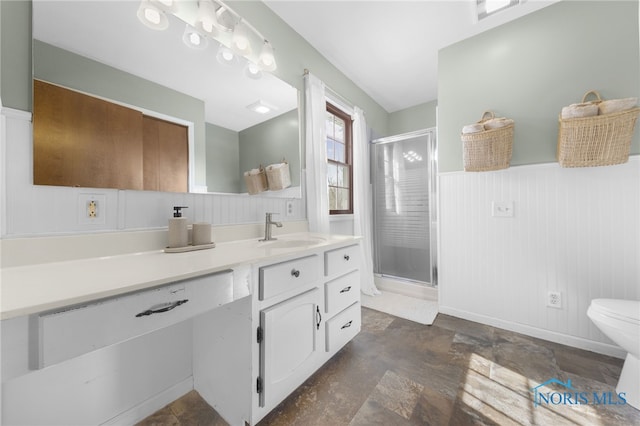 full bath featuring a stall shower, a wainscoted wall, vanity, and toilet