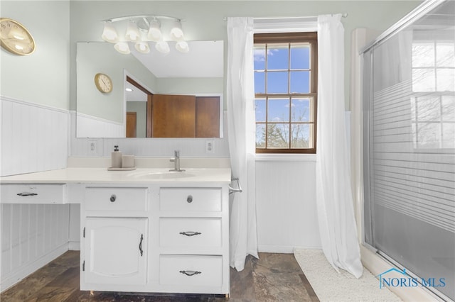 bathroom with a shower stall, vanity, and wainscoting