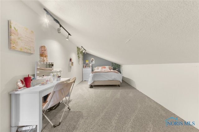 bedroom featuring carpet floors, rail lighting, vaulted ceiling, and a textured ceiling