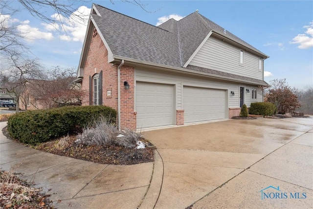 view of side of property with concrete driveway, brick siding, and roof with shingles