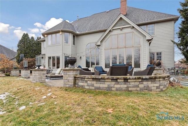 rear view of house featuring roof with shingles, a chimney, a patio area, and a lawn