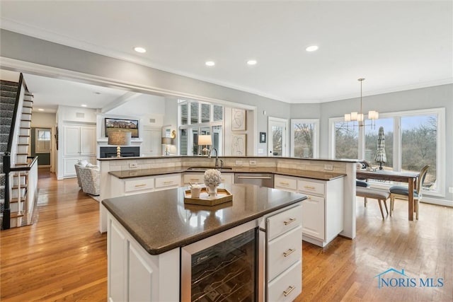 kitchen featuring light wood-style flooring, recessed lighting, beverage cooler, white cabinetry, and a center island