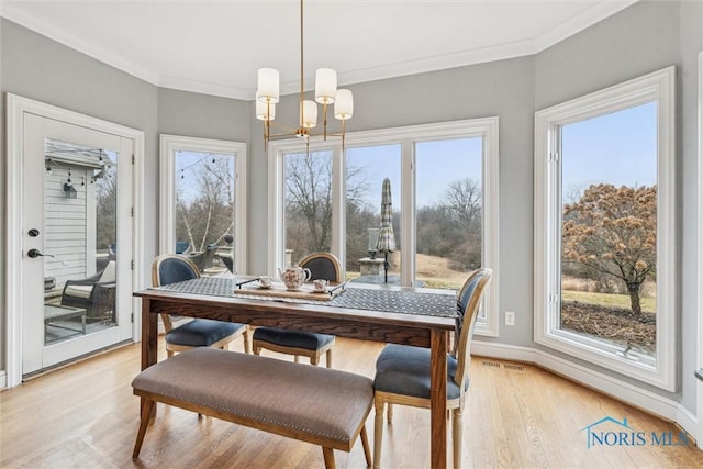 dining room with light wood finished floors, visible vents, baseboards, crown molding, and a notable chandelier