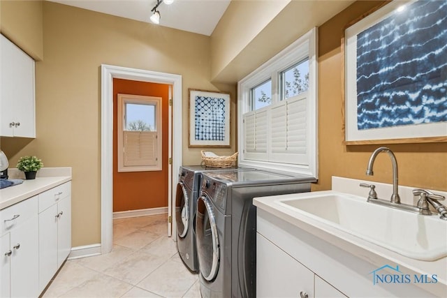 washroom with light tile patterned floors, separate washer and dryer, a sink, baseboards, and cabinet space