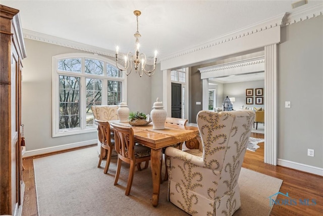 dining area with a notable chandelier, baseboards, wood finished floors, and ornamental molding