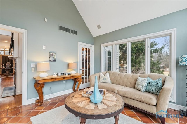 tiled living area featuring high vaulted ceiling, visible vents, and baseboards