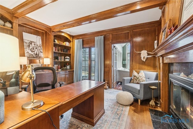 home office with wood walls, a premium fireplace, wood finished floors, built in features, and beamed ceiling