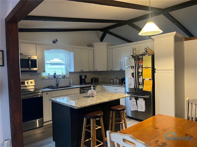 kitchen featuring tasteful backsplash, lofted ceiling with beams, a breakfast bar, stainless steel appliances, and a sink