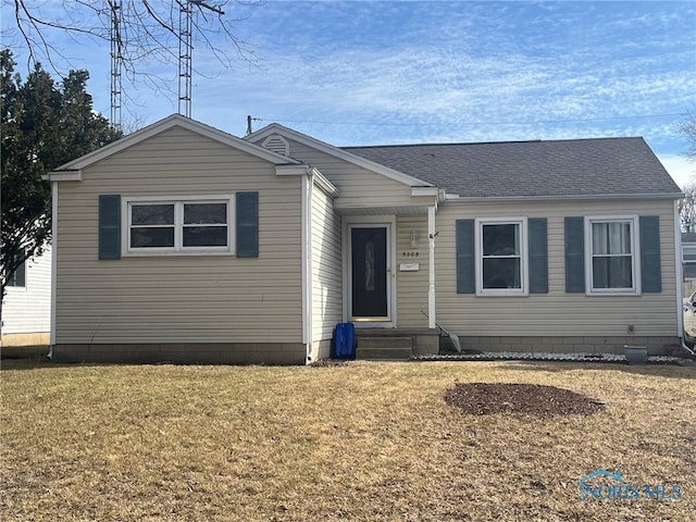 view of front facade with a front yard, roof with shingles, and entry steps