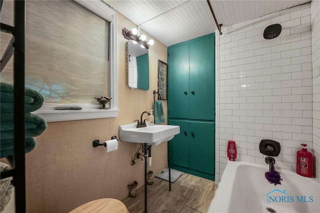 full bathroom with a sink, bathing tub / shower combination, and wood finished floors