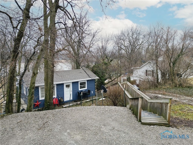 view of front of home featuring roof with shingles and fence