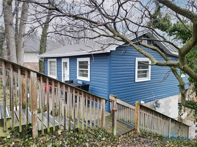 view of property exterior featuring roof with shingles and fence