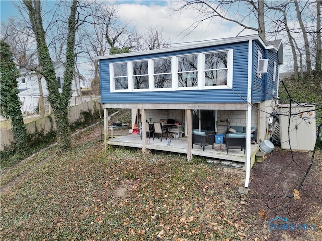 rear view of property featuring fence, a deck, and an outdoor hangout area