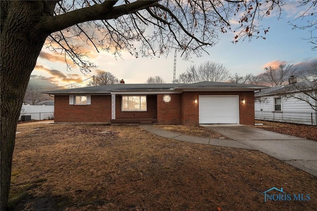 ranch-style home featuring a garage, brick siding, driveway, and fence