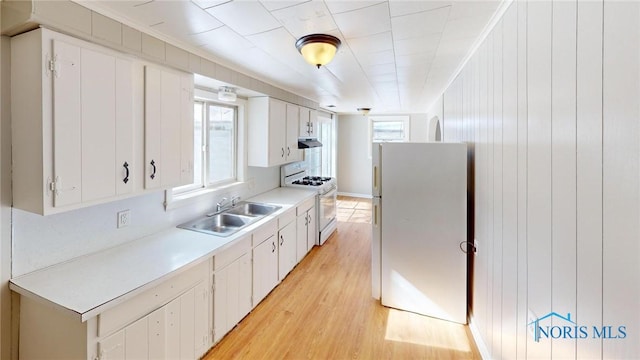 kitchen featuring light wood-style flooring, white appliances, a sink, white cabinets, and light countertops