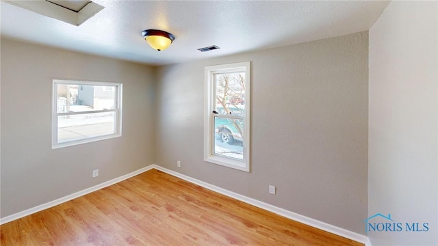 spare room featuring light wood-type flooring, baseboards, and visible vents