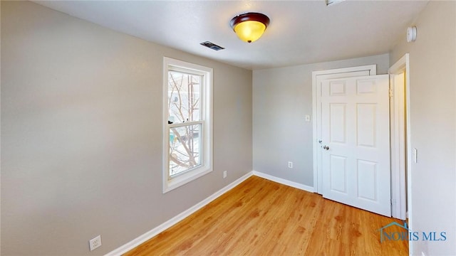 spare room with baseboards, a wealth of natural light, visible vents, and light wood-style floors