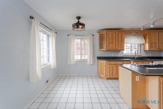 kitchen with dark countertops, a healthy amount of sunlight, a sink, and baseboards