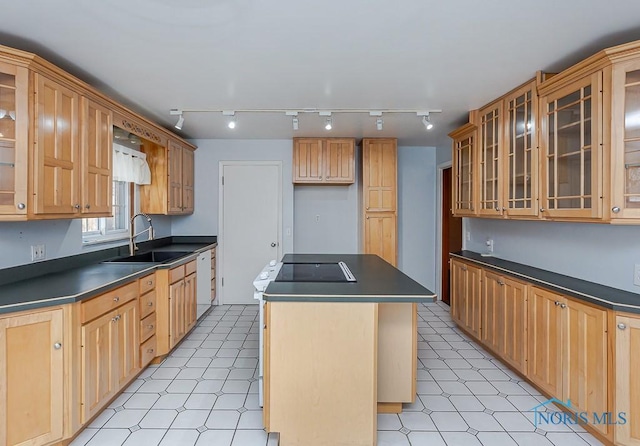 kitchen with a sink, a center island, dishwasher, light floors, and dark countertops