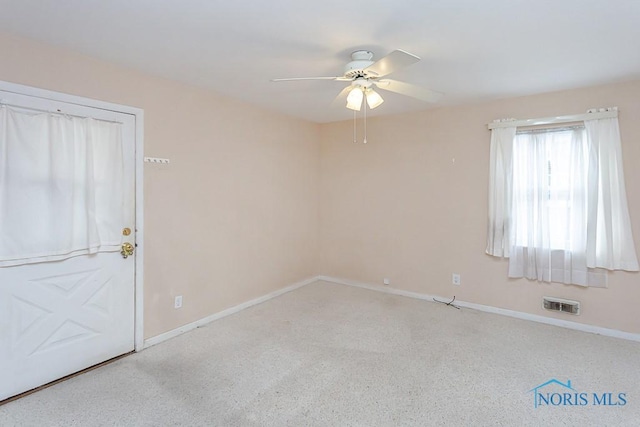 empty room featuring visible vents, ceiling fan, and baseboards