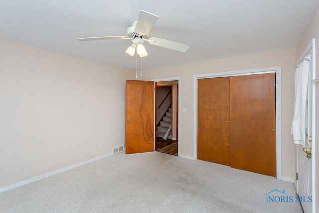 unfurnished bedroom featuring carpet, a closet, visible vents, a ceiling fan, and baseboards