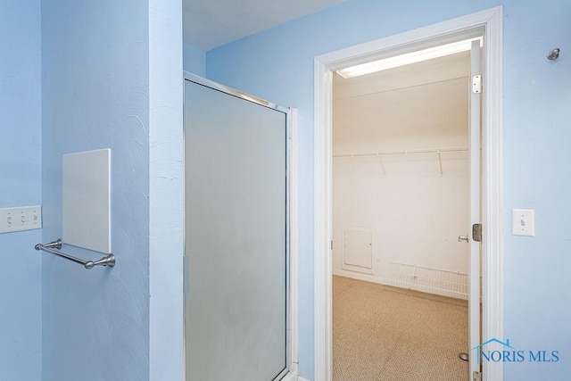 bathroom with an enclosed shower and a walk in closet