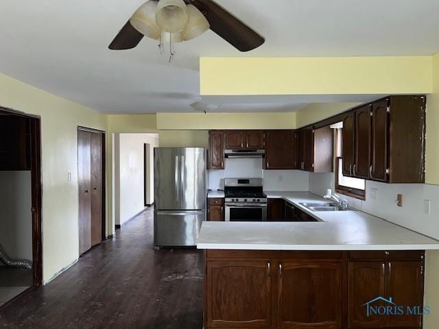 kitchen featuring dark brown cabinetry, stainless steel appliances, light countertops, under cabinet range hood, and a sink