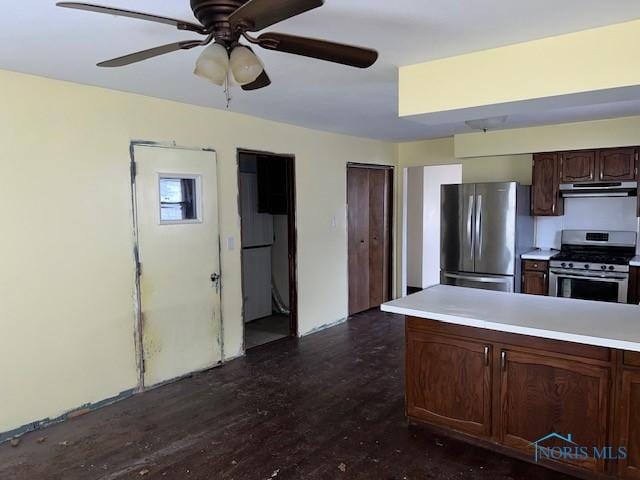 kitchen with under cabinet range hood, stainless steel appliances, dark wood-style flooring, a ceiling fan, and light countertops