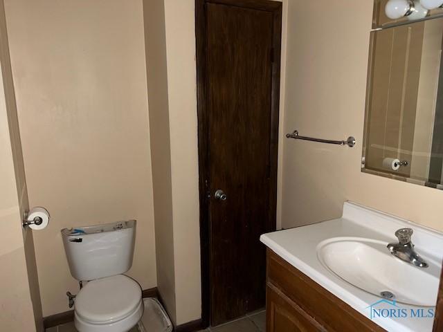 bathroom featuring toilet, vanity, and baseboards