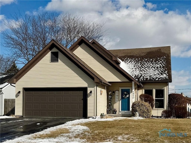 view of front of house featuring aphalt driveway, a lawn, an attached garage, and roof with shingles