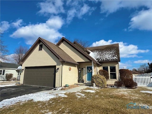 view of front of house featuring an attached garage, driveway, roof with shingles, and fence