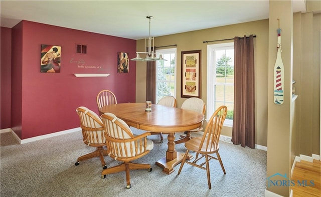 dining space featuring a chandelier, light carpet, an accent wall, visible vents, and baseboards