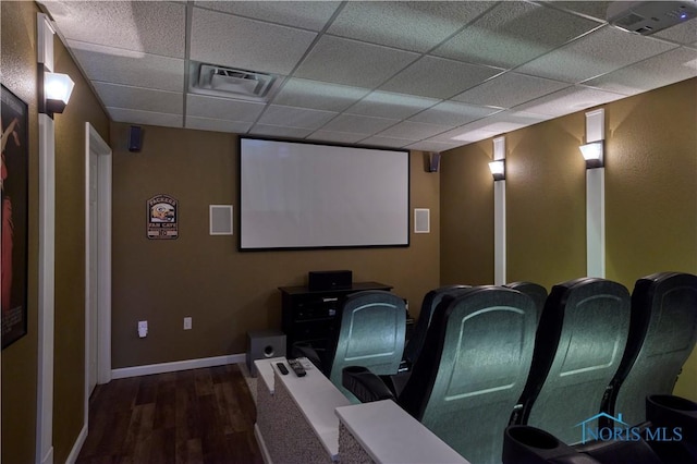 home theater room featuring baseboards, visible vents, a drop ceiling, and wood finished floors