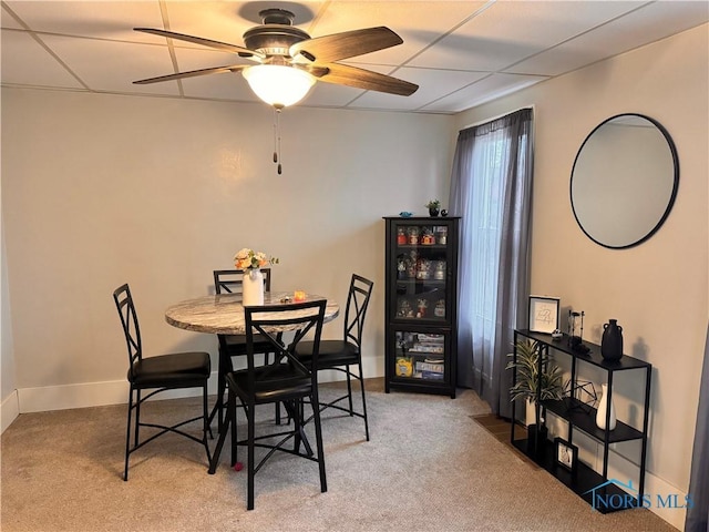 carpeted dining space featuring ceiling fan and baseboards