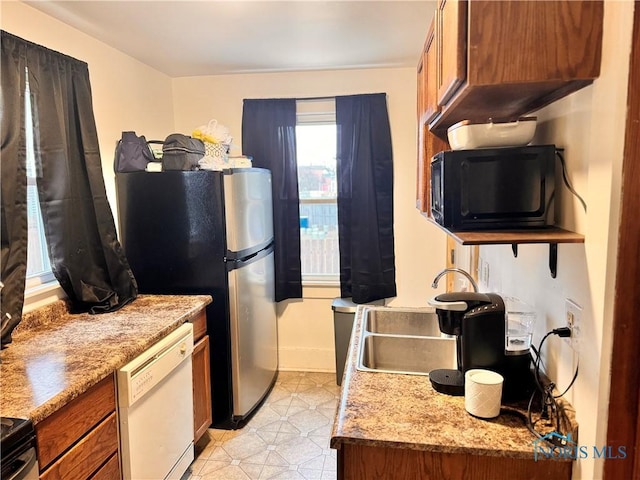 kitchen with black microwave, brown cabinets, white dishwasher, and a sink